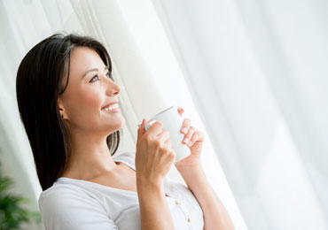 A lady drinking her coffee while the Hot Iron iron her garments