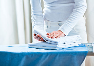A lady carefully folding ironed clothes